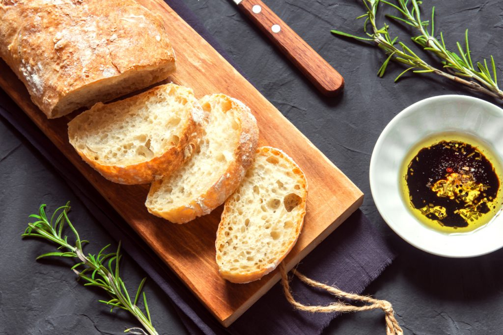 Italian bread Ciabatta Italian bread Ciabatta with olive oil and rosemary on black background - fresh