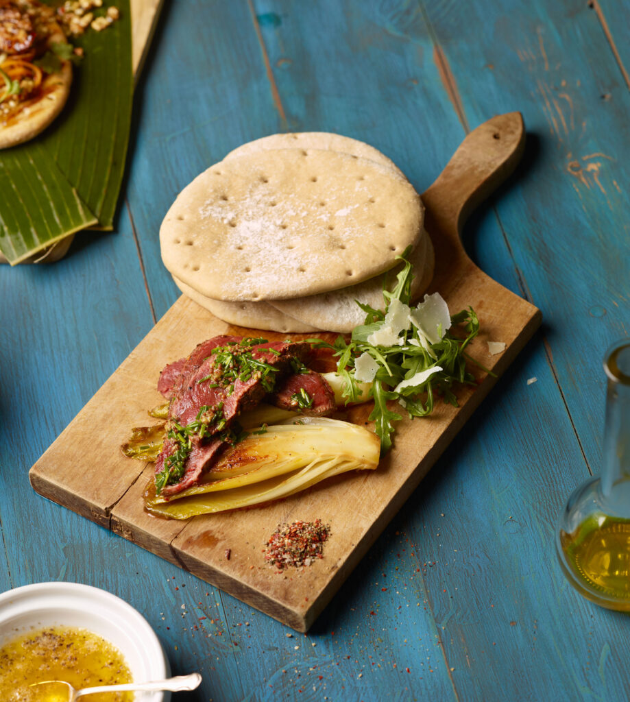 Griddled Sourdough Flatbreads with Truffle butter, Caramelized Chicory, Seared Pink Peppered Beef & Chive and Mustard Dressing. illustration