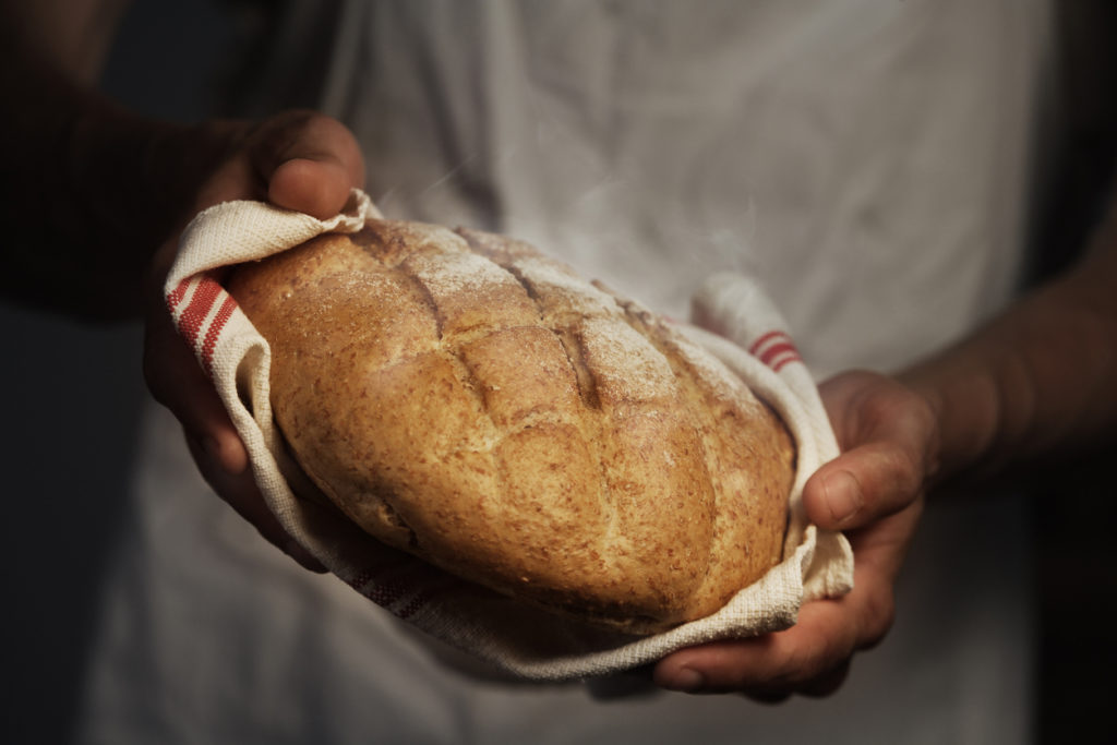 Baker man holding a warm loaf of bread